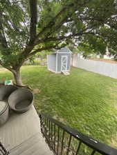 Fenced backyard featuring a storage unit