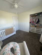 Bedroom featuring a closet, carpet flooring, ceiling fan, and a wainscoted wall