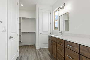 Full bath with vanity, wood finish floors, recessed lighting, and a walk in closet