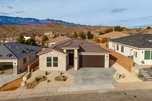 View of front of house with stucco siding, a residential view, a mountain view, driveway, and an attached garage