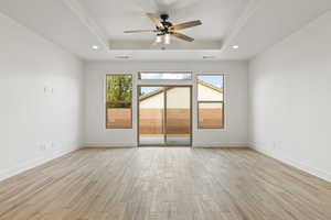 Empty room with wood tiled floors, a tray ceiling, ceiling fan, and recessed lighting