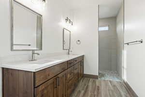Full bath with double vanity, wood finish floors, and walk in shower