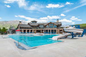 Community pool with a water slide, a mountain view, and a patio