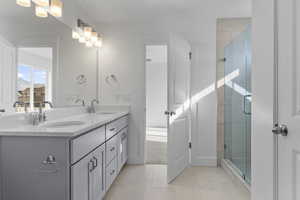Full bathroom featuring double vanity, a stall shower, and light tile patterned floors