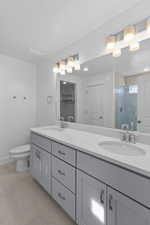 Full bath featuring a shower stall, double vanity, a spacious closet, and light tile patterned flooring