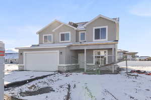 Traditional-style home featuring stone siding, an attached garage, and stucco siding