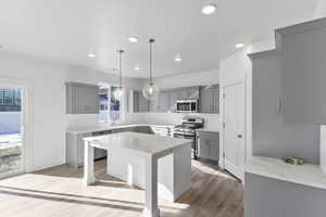 Kitchen with gray cabinetry, appliances with stainless steel finishes, a center island, pendant lighting, and recessed lighting