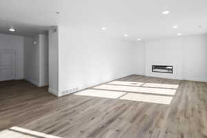 Unfurnished living room featuring recessed lighting, wood finished floors, and a glass covered fireplace