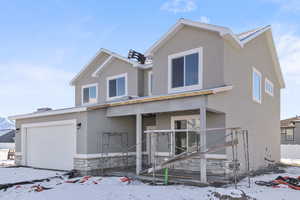 View of front of home with a garage, stucco siding, and stone siding