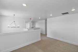 Unfurnished room featuring light colored carpet, a chandelier, and recessed lighting
