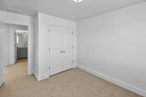 Unfurnished bedroom featuring light colored carpet and a closet