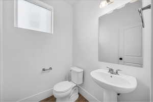 Half bath with baseboards and wood finished floors