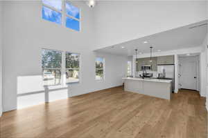 Kitchen featuring a center island with sink, gray cabinets, open floor plan, light wood finished floors, and recessed lighting