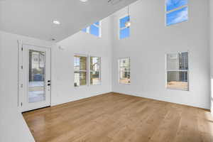Foyer with light wood-style flooring, a towering ceiling, and recessed lighting