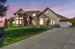 French country style house featuring a front lawn, stone siding, stucco siding, concrete driveway, and an attached garage