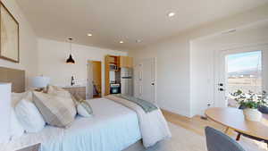 Bedroom with light wood-type flooring, recessed lighting, freestanding refrigerator, and ensuite bath