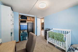 Bedroom with a nursery area, light colored carpet, and a closet