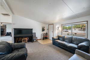 Carpeted living area featuring vaulted ceiling