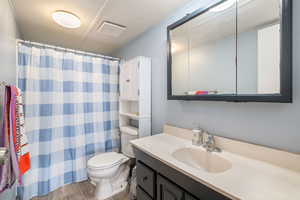 Full bath with dark wood finished floors, vanity, and a shower with shower curtain