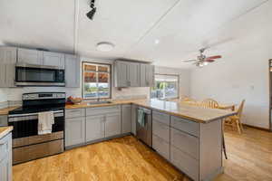 Kitchen featuring appliances with stainless steel finishes, gray cabinetry, and light wood finished floors