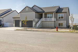 Craftsman-style house with stone siding, a porch, concrete driveway, a garage, and roof with shingles