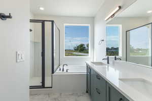 Full bathroom with a shower stall, double vanity, a garden tub, light marble finish flooring, and healthy amount of natural light