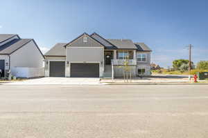 View of front facade featuring board and batten siding, stone siding, concrete driveway, and a garage
