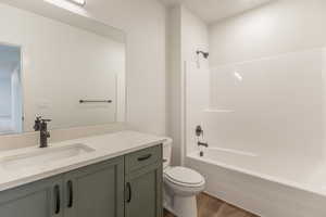 Bathroom featuring tub / shower combination, vanity, and dark wood-type flooring