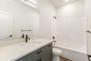 Bathroom with tub / shower combination, vanity, and dark wood finished floors