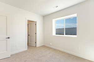 Unfurnished bedroom with light carpet and baseboards