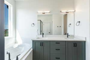 Full bath featuring double vanity, a shower stall, and a bath