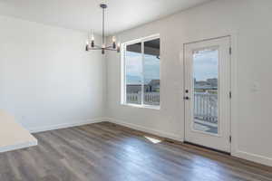 Unfurnished dining area featuring dark wood-style floors and a chandelier