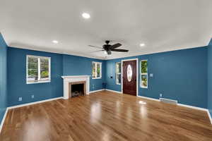 Unfurnished living room with wood finished floors, healthy amount of natural light, a tile fireplace, a ceiling fan, and recessed lighting