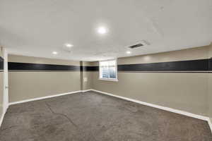 Below grade area with a textured ceiling, carpet floors, and recessed lighting