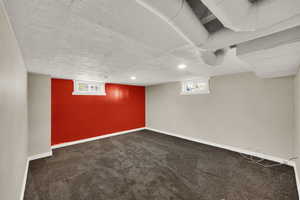 Basement featuring dark colored carpet and a textured ceiling