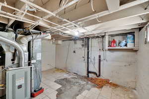Unfinished below grade area featuring heating unit and tile patterned flooring