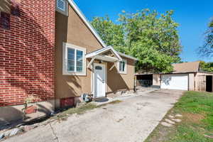 View of exterior entry featuring stucco siding, concrete driveway, and a detached garage