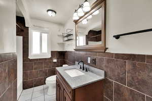 Full bathroom featuring light tile patterned floors, vanity, plenty of natural light, tile walls, and shower / bath combination