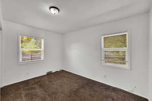 Empty room featuring plenty of natural light, dark colored carpet, and a textured ceiling