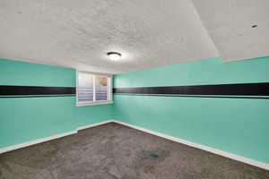 Empty room with a textured ceiling and dark carpet