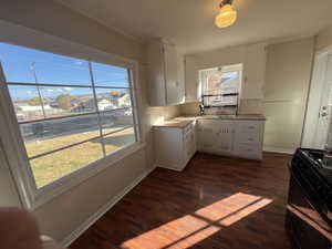 Kitchen with white cabinets, light countertops, black range with gas cooktop, dark wood-style floors, and ornamental molding