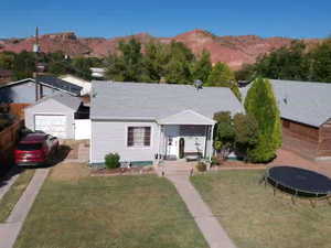 View of front of house featuring a trampoline, a mountain view, a front lawn, and a shingled roof