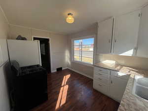 Kitchen with white cabinetry, black range with gas cooktop, dark wood-style flooring, crown molding, and light stone counters