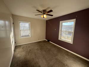 Spare room with dark carpet, plenty of natural light, and ceiling fan