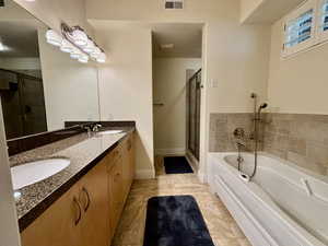 Full bathroom featuring a garden tub, double vanity, and a shower stall
