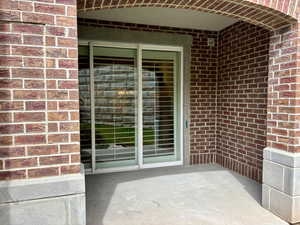 Property entrance with brick siding and a patio area