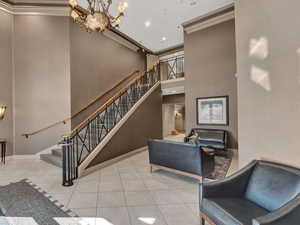 Staircase featuring crown molding, a high ceiling, tile patterned floors, a chandelier, and recessed lighting