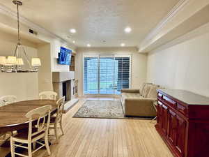 Living area featuring a tile fireplace, light wood-style floors, ornamental molding, a textured ceiling, and recessed lighting