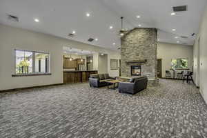 Living room featuring high vaulted ceiling, dark colored carpet, a fireplace, ceiling fan, and recessed lighting
