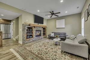 Living room featuring recessed lighting, light wood-style floors, ceiling fan, and a stone fireplace
